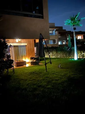 a yard with an umbrella in the grass at night at Prestigia golf city porte agate in Marrakech