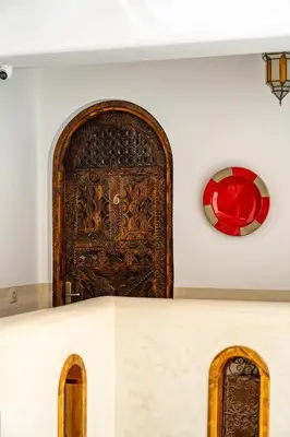 a large wooden door in a wall with a window at Riad Nalan & Spa in Marrakech