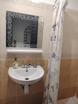 a bathroom with a sink and a mirror and a shower curtain at Appartement résidence avec piscine in Marrakech