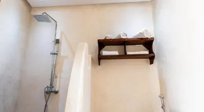 a bathroom with a shower and a sink with towels at Riad 4 Jardins & Spa in Marrakech