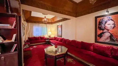 a living room with a red couch and a painting at Flair's - Families Only in Marrakech