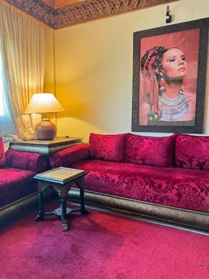 a living room with a red couch and a painting at Flair's - Families Only in Marrakech