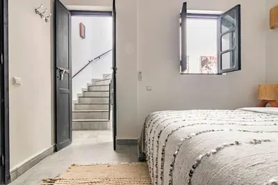 a white bedroom with a bed and a staircase at Maison Meurisse Marrakech in Marrakech