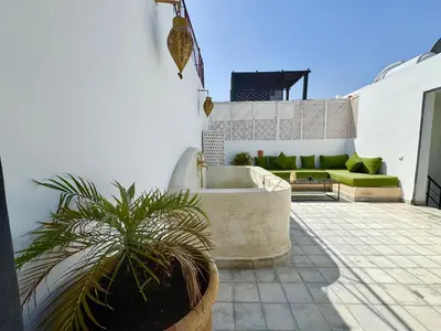a patio with a couch and a plant at Maison Meurisse Marrakech in Marrakech