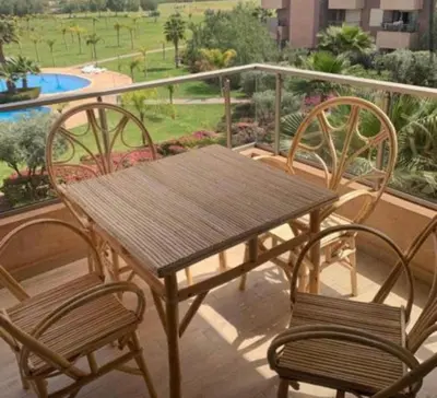 a wooden table and two chairs on a balcony at Prestigia jade Marrakech ENTREE 191 APPARTEMENT 9 in Marrakech