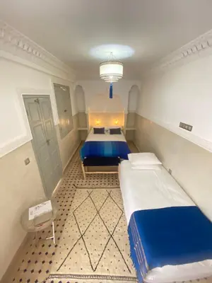 a bedroom with two beds and a chandelier at Riad privatisé Magnolia in Marrakech