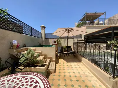 a patio with an umbrella and tables and chairs at Riad privatisé Magnolia in Marrakech