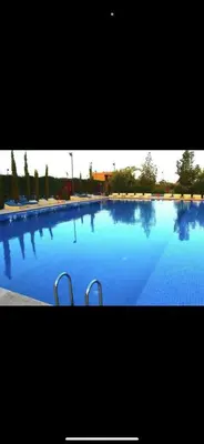 a large swimming pool with blue water and two handles at Magnifique villa avec piscine chauffée in Marrakech