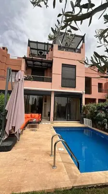 a house with a swimming pool and an umbrella at Magnifique villa avec piscine chauffée in Marrakech