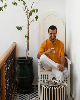 a man sitting in a chair with a cup of coffee at Riad Botanica in Marrakech