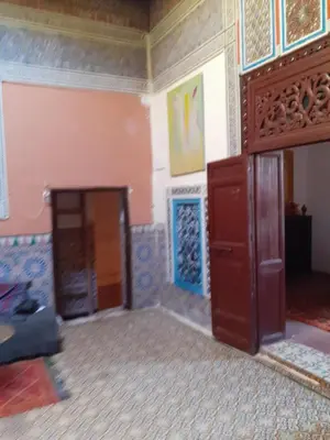 a living room with a wooden door and a wall at Maison authentique centre médina in Marrakech