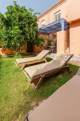 a row of chaise lounges on the grass near a building at Villa Kalthoum in Marrakech