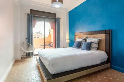 a bedroom with a large bed with a blue wall at Magnifique villa de 320 m2 avec 2 piscines in Marrakech