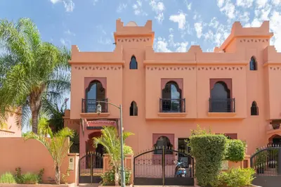 a pink building with palm trees in front of it at Magnifique villa de 320 m2 avec 2 piscines in Marrakech