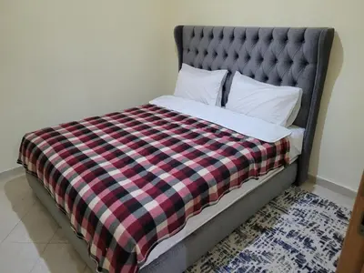 a bed with a plaid blanket and pillows at Basic appartement avec Parking in Marrakech