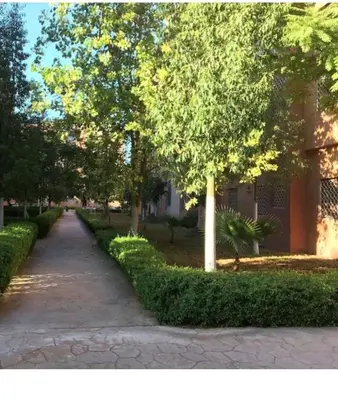a path in a park with trees and a building at Basic appartement avec Parking in Marrakech