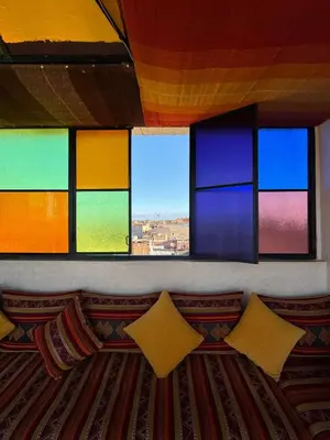a room with colorful windows and a couch with pillows at Riad Malayine in Marrakech