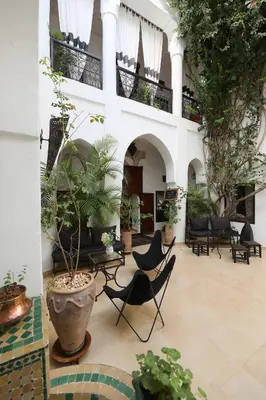 a courtyard with chairs and plants in a building at Riad Noor Charana in Marrakech