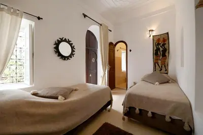 a bedroom with two beds and a window and a mirror at Riad Noor Charana in Marrakech
