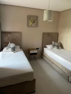 a bedroom with two beds and a side table at Appartement de luxe Prestigia Opale in Marrakech