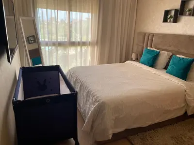 a bedroom with a bed with blue pillows and a window at Appartement de luxe Prestigia Opale in Marrakech