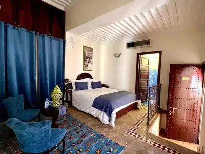 a bedroom with a bed and chairs in a room at Riad Sassa Finda in Marrakech