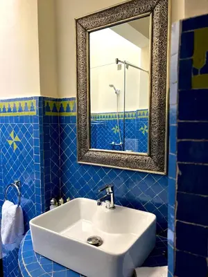 a blue tiled bathroom with a sink and a mirror at Riad Sassa Finda in Marrakech