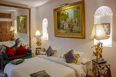 a bedroom with two beds and a painting on the wall at Riad Esmeralda in Marrakech