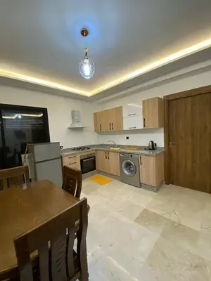 a kitchen with a table and a kitchen with a dishwasher at Appartement de luxe Marrakech Gueliz in Marrakech