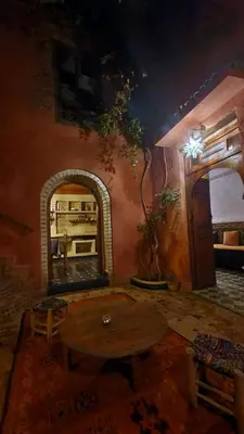 a living room with a table and a fireplace at Beldi Riad in Marrakech