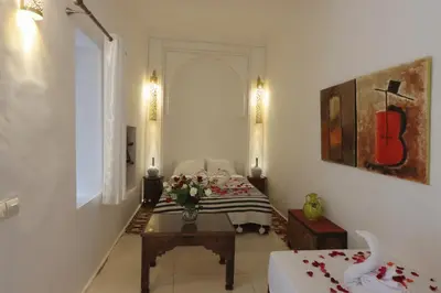 a living room with a table and a bed at Riad Jenan L'mouassine in Marrakech