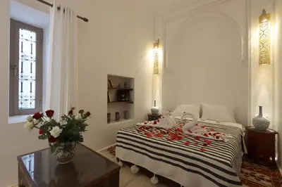 a bedroom with a bed with a table and a vase of flowers at Riad Jenan L'mouassine in Marrakech