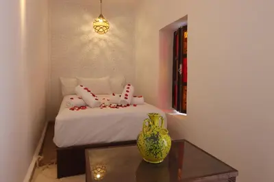 a bedroom with a bed with a table and a vase at Riad Jenan L'mouassine in Marrakech