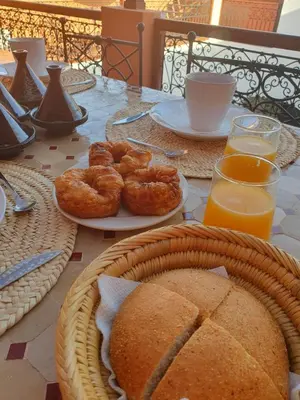 a table with plates of bread and onion rings and orange juice at Riad Le Manzil Beldi in Marrakech