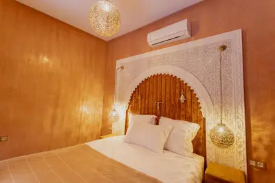 a bedroom with a bed with a wooden headboard at RIAD MARRAKECH DOORS in Marrakech
