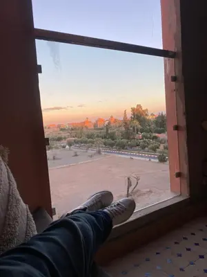 a person sitting on a window looking out at a view at Appartment le bleu in Marrakech