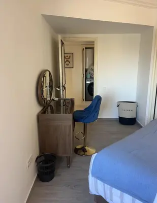 a bedroom with a bed and a chair and a mirror at Appartment le bleu in Marrakech