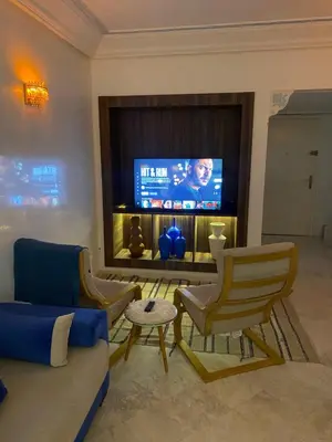 a living room with a couch and chairs and a tv at Appartment le bleu in Marrakech