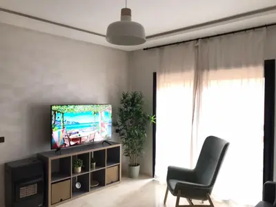 a living room with a television and a chair at Superbe appartement uniquement pour les familles in Marrakech