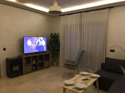 a living room with a couch and a tv at Superbe appartement uniquement pour les familles in Marrakech