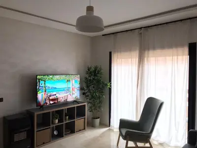 a living room with a television and a chair at Superbe appartement uniquement pour les familles in Marrakech