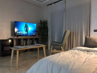 a bedroom with a bed and a tv and a table at Superbe appartement uniquement pour les familles in Marrakech