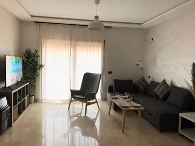 a living room with a black couch and a table at Superbe appartement uniquement pour les familles in Marrakech