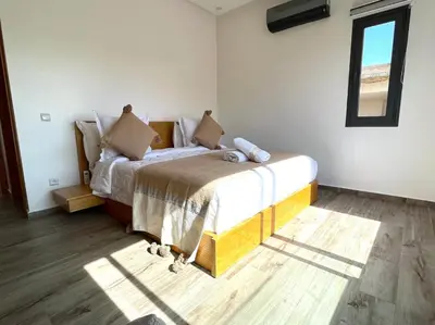 a bedroom with a bed with white sheets and a window at Belle et spacieuse villa au Golf Amelkis Marrakech in Marrakech