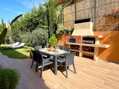 a patio with a table and a pizza oven at Belle et spacieuse villa au Golf Amelkis Marrakech in Marrakech