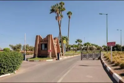 an empty street with a building and palm trees at appartement in Marrakech