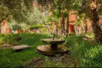 a fountain in the middle of a yard with trees at appartement in Marrakech
