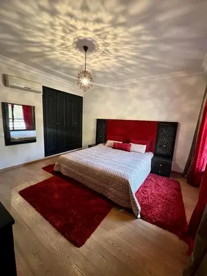 a bedroom with a large bed and a red rug at Appartement chambre salon a l'hivernage 9 in Marrakech