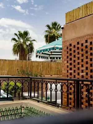 a patio with a fence and an umbrella and palm trees at Riad Casa Felicità & SPA in Marrakech