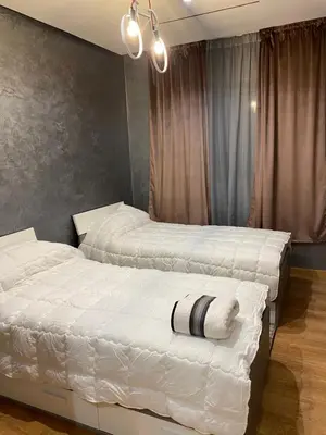 two beds in a bedroom with white sheets at Appartement a loué pour les familles in Marrakech